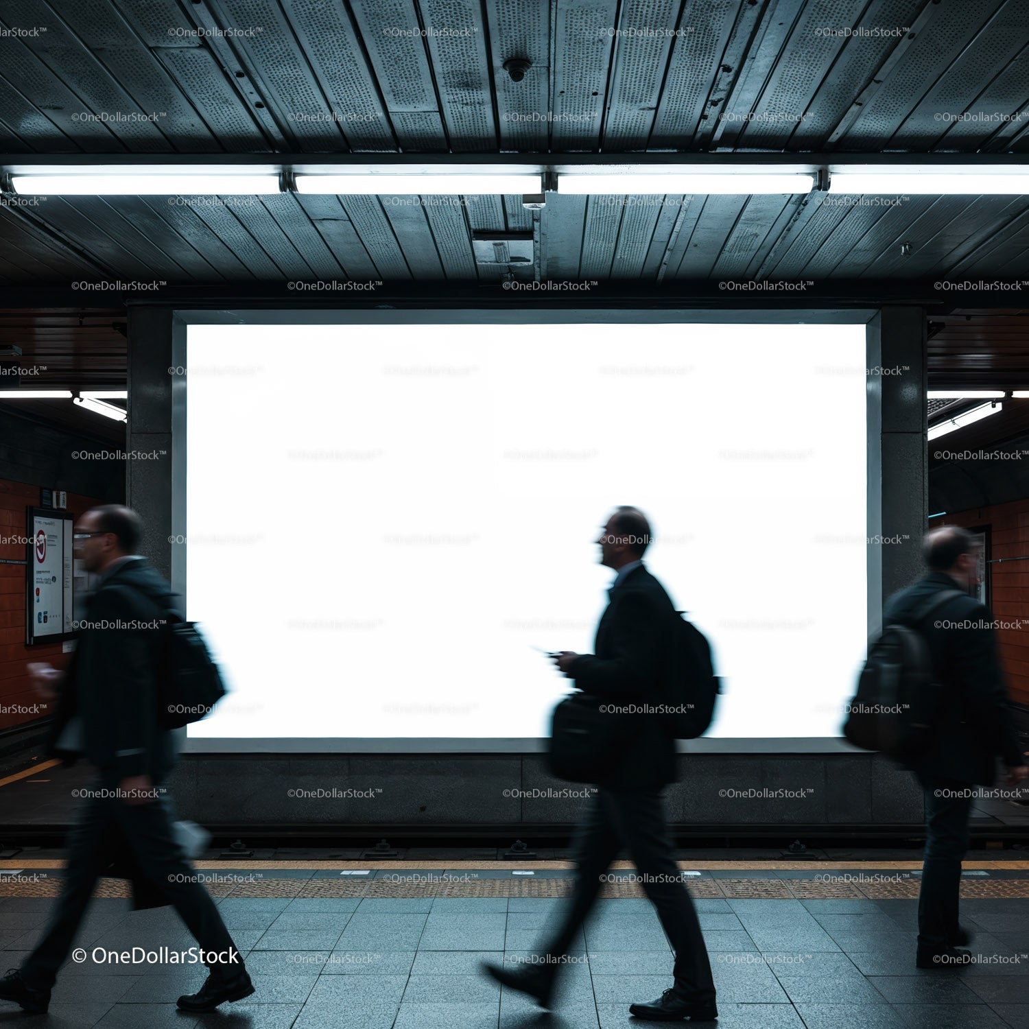 Pasażerowie przechodzący obok pustego, oświetlonego billboardu w metrze