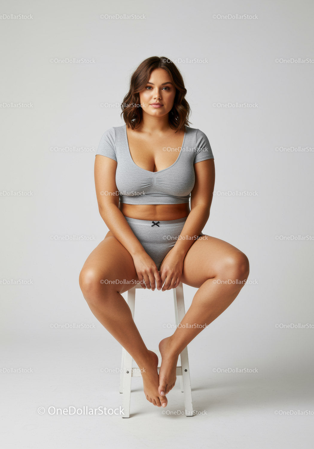 Confident Young Woman Sitting on Stool Wearing Casual Gray Outfit