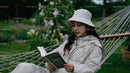 Young Woman Relaxing and Reading in Garden Hammock