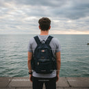 Young Man Standing by the Seaside with Backpack Enjoying Sunset