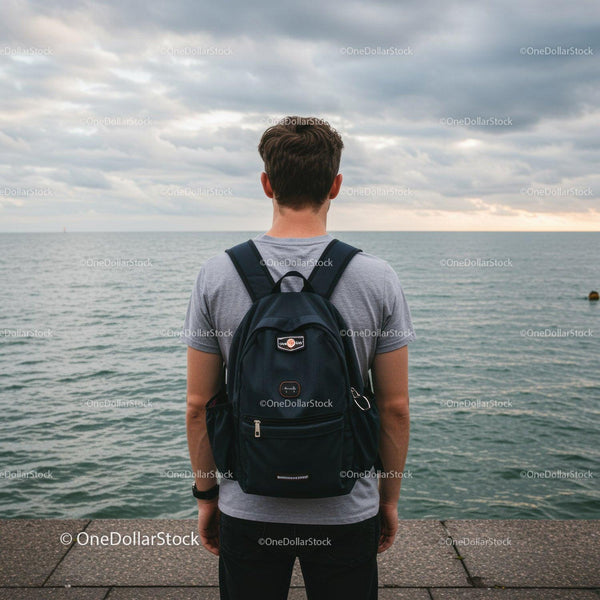 Young Man Standing by the Seaside with Backpack Enjoying Sunset