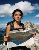 Woman exploring mountain trails using a map on a sunny day