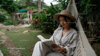 Young Woman Relaxing in Hammock Reading Book Surrounded by Tropical Garden