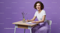 Happy Woman Writing Notes in a Stylish Purple Workspace
