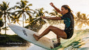 Young Woman Surfing a Wave at Sunset with Palm Trees