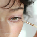 Close-up of a woman applying eye makeup with a makeup brush