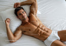 Fit young man relaxing on bed in white underwear
