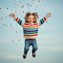 Joyful child jumping with colorful confetti outdoors