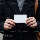 Person holding a blank white business card outdoors