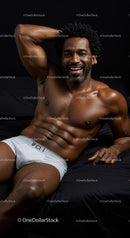 Smiling muscular man relaxing on black bedding