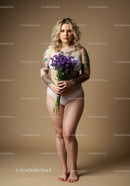 Confident Curvy Woman with Tattoos Holding Purple Flower Bouquet Studio Portrait