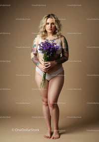 Confident Curvy Woman with Tattoos Holding Purple Flower Bouquet Studio Portrait