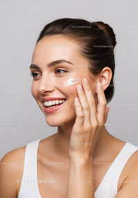 Young Woman Applying Skincare Cream with Bright Smile for Radiance