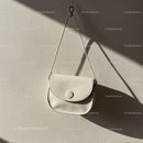 Minimalist white leather handbag hanging on wall