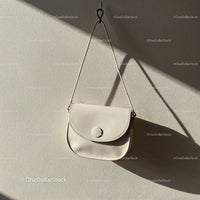 Minimalist white leather handbag hanging on wall