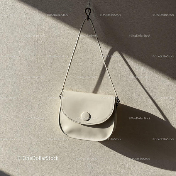 Minimalist white leather handbag hanging on wall JPG Mockup Image
