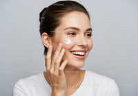 Young Woman Applying Facial Moisturizer Smiling Skincare Routine