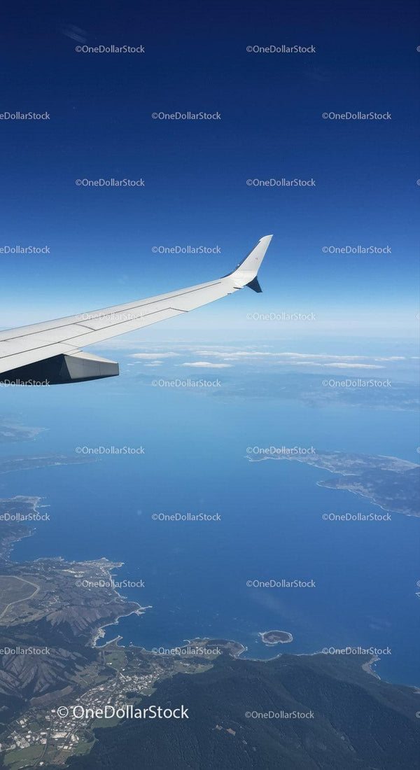 Aerial View of Airplane Wing Over Coast and Mountains