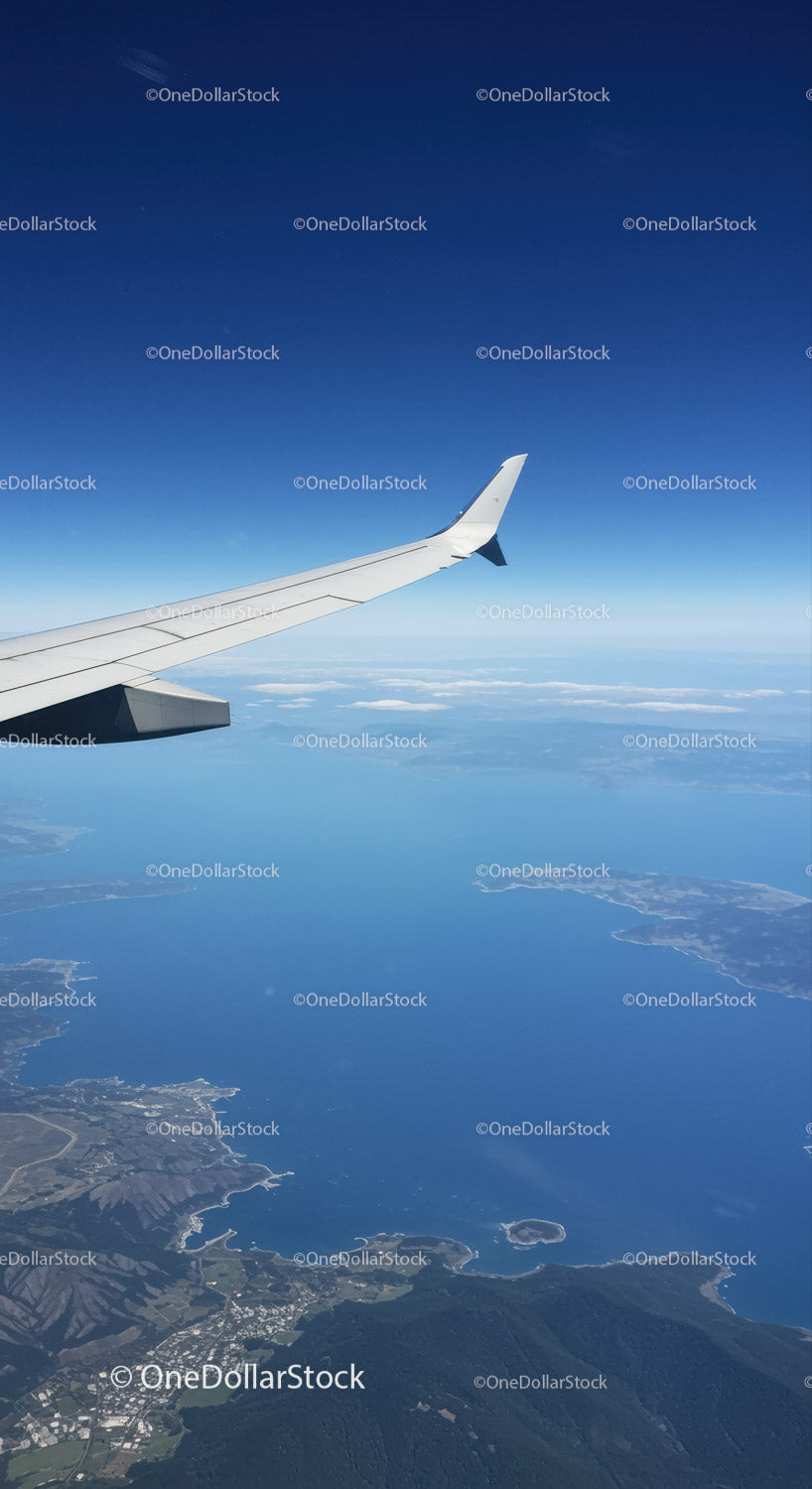 Aerial View of Airplane Wing Over Coast and Mountains