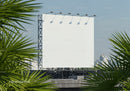 Blank billboard on rooftop framed by palm leaves