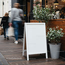 Blank white sidewalk board outside modern cafe entrance