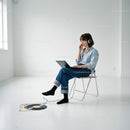 Young woman sitting with laptop and headphones near vinyl record