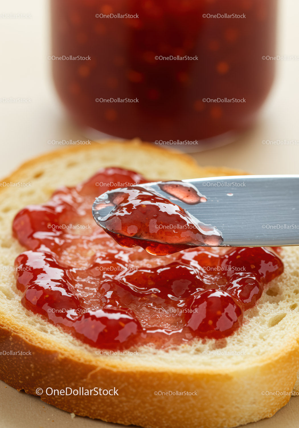 Knife Spreading Strawberry Jam on Fresh Bread Slice