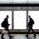 Blurred commuters walking past blank urban advertisements