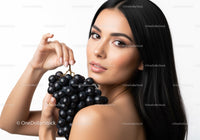 Elegant Woman Holding Black Grapes in a Bright Studio Setting