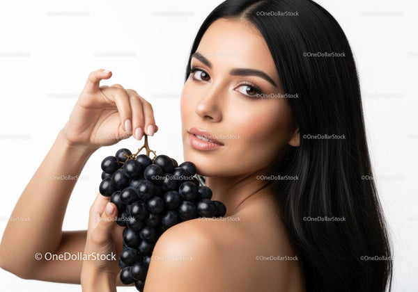 Elegant Woman Holding Black Grapes in a Bright Studio Setting