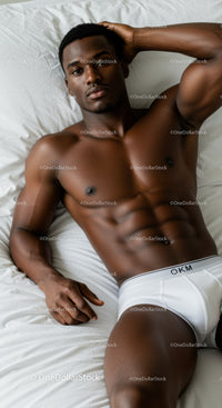 Relaxed fit young man lying on white bed sheets