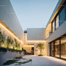Modern minimalist white concrete building with glass windows and landscaped garden
