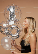 Smiling woman holding balloons celebrating first birthday