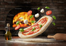 Fresh pizza dough with toppings tossed near wood oven