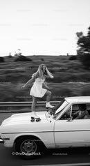 Young woman roller skating on classic car on road
