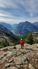 Hiker in red jacket exploring mountainous valley landscape