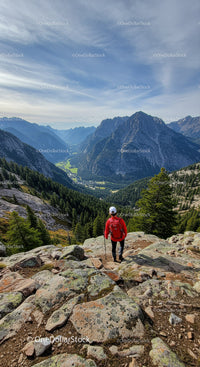 Hiker in red jacket exploring mountainous valley landscape