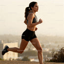 Focused Young Woman Running Outdoors at Sunset