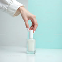 Beautiful woman applying white nail polish with a modern background