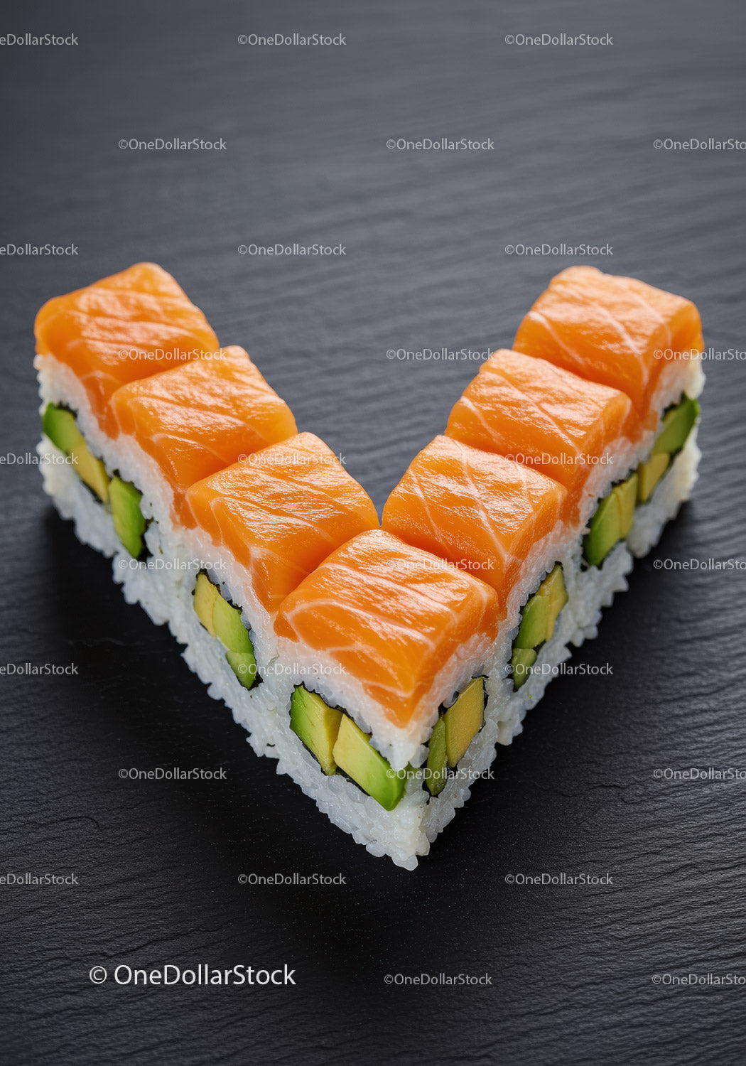 Fresh salmon avocado sushi rolls arranged on black slate