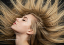 Blonde woman with flowing hair lying against dark background
