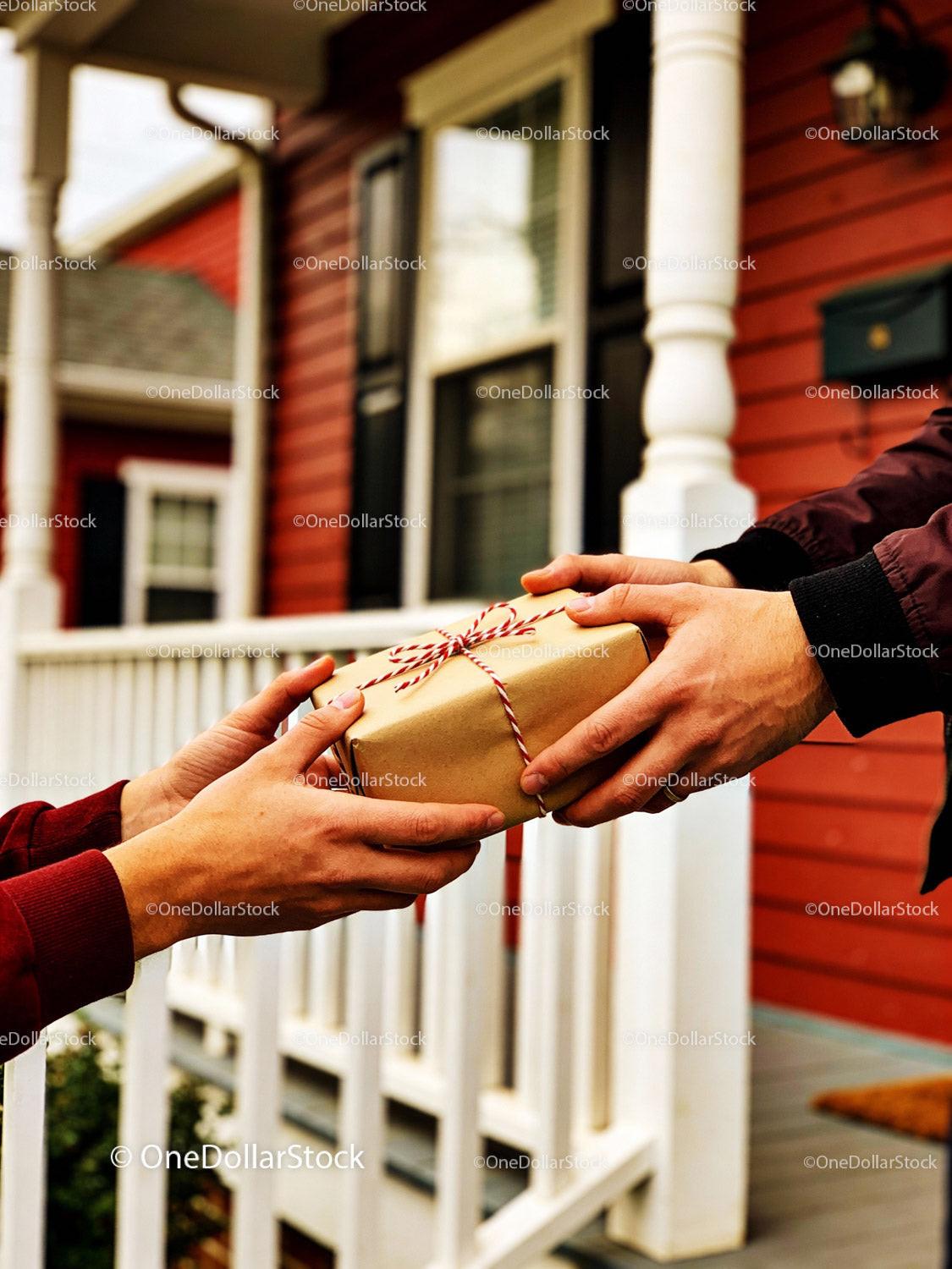 Exchanging a wrapped gift outside a charming red house