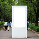 Blank white billboard in busy green city park walkway