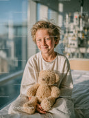 Joyful Child with Teddy Bear in Bright Hospital Room