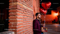 Man holding heart balloons and chocolate gift at night