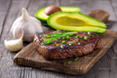 Juicy Grilled Steak with Fresh Avocado and Garlic on Wooden Board