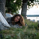 Serene Woman Resting on Grass by Lake in Outdoor Camping Scene