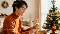 Young man decorating Christmas tree with golden reindeer