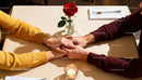 Couple Holding Hands Across Romantic Candlelit Table