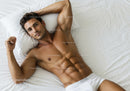 Relaxed young man lying on bed in white underwear